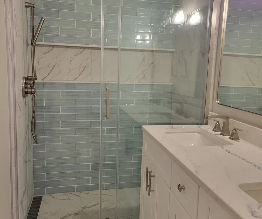 Ceramic shower tile and custom glass enclosure detail from a bathroom renovation
